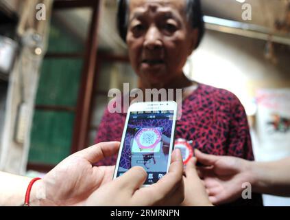 (140729) -- HEFEI, Juli 29, 2014 (Xinhua) -- Arbeiter scannen die zweidimensionale Code-Karte nach Qiao Zonglian, einer 84-jährigen Frau, in der Gemeinde Dingxiang in Hefei, der Hauptstadt der ostchinesischen Provinz Anhui, am 29. Juli 2014. Die Dingxiang-Gemeinde in Hefei verteilte die erste Reihe persönlicher zweidimensionaler Code-Karten an Personen über 80 Jahren. Die Karte kann dem Halter die grundlegende Verformung geben, wenn er verloren geht. (Xinhua/Liu Junxi) (hpj) CHINA-HEFEI-ZWEIDIMENSIONALE CODE-KARTE (CN) PUBLICATIONxNOTxINxCHN Hefei JUL y 29 2014 XINHUA Arbeiter Scannen Sie die zweidimensionale Code-Karte für Qiao an 84 Jahre alte Frau in Stockfoto