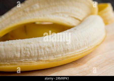 Geschälte reife gelbe Banane, Bananenstückchen zum Dessert-Kochen ist auf dem Board Stockfoto