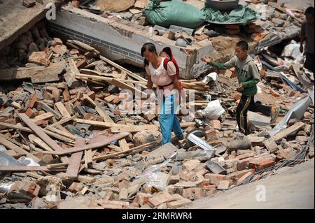 (140805) -- LUDIAN, 5. August 2014 -- Menschen gehen an zusammengebrochenen Häusern in der Longtoushan Township des Ludian County, südwestchinesische Provinz Yunnan, 5. August 2014. Das Erdbeben der Stärke 6,5, das das Ludian County von Yunnan am Sonntagnachmittag erschütterte, hat mindestens 410 Menschen getötet, 12 vermisst und mehr als 2.300 andere verletzt. ) (Ry) CHINA-YUNNAN-EARTHQUAKE-RESCUE(CN) XuexYubin PUBLICATIONxNOTxINxCHN 5. August 2014 Prominente gehen an eingestürzten Häusern in der Gemeinde County Südwest China S Yunnan Province 5. August 2014 das Erdbeben der Stärke 6 5 hat Yunnan S County AM Sonntag Mittag getroffen Stockfoto