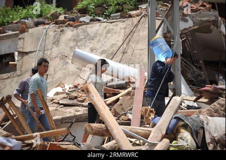 (140805) -- LUDIAN, 5. August 2014 -- Menschen gehen an zusammengebrochenen Häusern in der Longtoushan Township des Ludian County, südwestchinesische Provinz Yunnan, 5. August 2014. Das Erdbeben der Stärke 6,5, das das Ludian County von Yunnan am Sonntagnachmittag erschütterte, hat mindestens 410 Menschen getötet, 12 vermisst und mehr als 2.300 andere verletzt. ) (Ry) CHINA-YUNNAN-EARTHQUAKE-RESCUE(CN) XuexYubin PUBLICATIONxNOTxINxCHN 5. August 2014 Prominente gehen an eingestürzten Häusern in der Gemeinde County Südwest China S Yunnan Province 5. August 2014 das Erdbeben der Stärke 6 5 hat Yunnan S County AM Sonntag Mittag getroffen Stockfoto