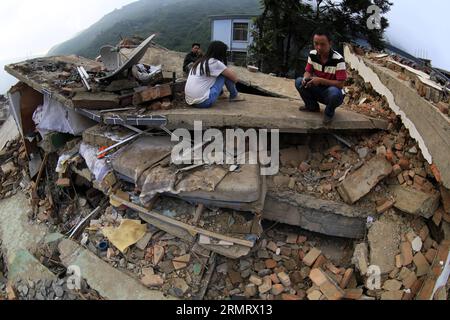 (140805) -- ZHAOTONG, 5. August 2014 -- Menschen sitzen auf den Ruinen eines Hauses, das durch ein Erdbeben von 6,5 Magnitude in der Longtoushan Township des Ludian County, südwestchinesische Provinz Yunnan, 5. August 2014 beschädigt wurde. Das Erdbeben der Stärke 6,5, das das Ludian County von Yunnan am Sonntagnachmittag erschütterte, hat mindestens 410 Menschen getötet, 12 vermisst und mehr als 2.300 andere verletzt. ) (hpj) CHINA-YUNNAN-ZHAOTONG-DAMAGED HOUSES(CN) ZhangxGuangyu PUBLICATIONxNOTxINxCHN Zhao Tong 5. August 2014 Prominente sitzen AUF den Ruinen eines Hauses, das durch ein Erdbeben der Stärke 6 5 in der Gemeinde County Südwest China S Yu beschädigt wurde Stockfoto