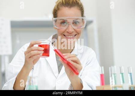 Glückliche Frau Wissenschaftler Zugabe von Flüssigkeit zu Reagenzglas Stockfoto