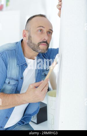 Ein reifer Mann, der Wand im Haus malte Stockfoto