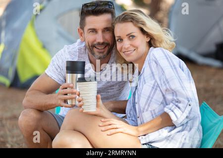 Ein Paar auf dem Campingausflug, das Tassen am Zelt hält Stockfoto