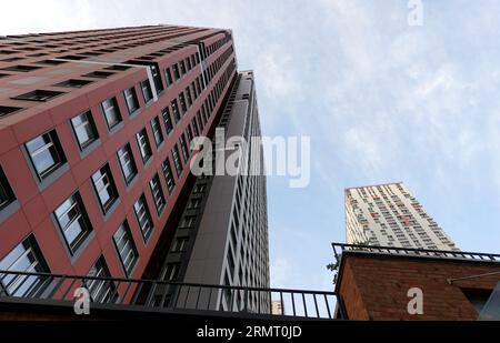 Blick von unten nach oben auf hochmoderne Wolkenkratzergebäude mit vielen Fenstern im urbanen Cluster Stockfoto