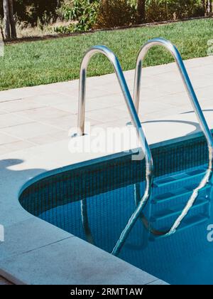 Blick auf den Swimmingpool im Sommer mit Treppen und grünem Gras. Private Villa. Entspannender Außenbereich. Vorderansicht Stockfoto