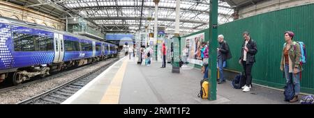 Passagiere, die auf dem Bahnsteig 19 auf den Zug warten, Scotrail-Zug auf dem angrenzenden Bahnsteig, Waverley Station, Edinburgh Stockfoto