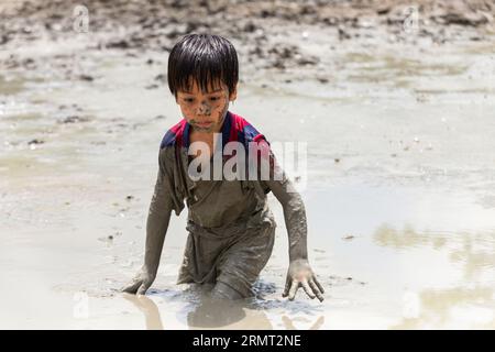 Süßer, glücklicher kleiner asiatischer Junge, der gerne im Schlamm auf dem Spielplatz spielt. Kindererziehung in der Natur an der montessori-Schule. Natur- und Bildungskonzept. Stockfoto