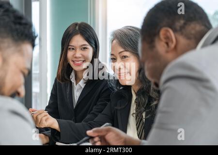 Glückliche Arbeit mit verschiedenen, unterschiedlichen Altersgruppen und multiethnischen Geschäftsteams. Führungskraft und Mitarbeiter sprechen im Besprechungsraum im Büro Stockfoto