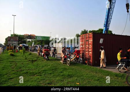 (140815) -- ISLAMABAD, -- Unterstützer des pakistanischen Cricketers Imran Khan passieren am 14. August 2014 eine Straße, die von einem Schiffscontainer auf der Schnellstraße in Islamabad, der Hauptstadt Pakistans, blockiert wurde. Tausende Demonstranten sind aus der pakistanischen Stadt Lahore aufgebrochen, um in der Hauptstadt zu marschieren, um die Regierung zu entlasten, von der sie behaupten, sie sei durch Betrug gewählt worden. )(hdt) PAKISTAN-ISLAMABAD-MARCH AhmadxKamal PUBLICATIONxNOTxINxCHN Islamabad Anhänger des pakistanischen Cricketers wurden Politiker Imran Khan Passport durch eine Straße blockiert durch einen Schiffscontainer AUF der Schifffahrtsstraße in Islama Stockfoto