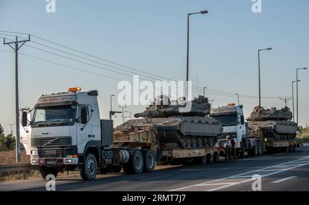 (140820) -- GAZA-GRENZE, 20. August 2014 -- Menschen reparieren einen LKW, der einen Merkava-Tank auf der Straße in Südisrael am Rande des Gazastreifens transportiert, am 20. August 2014. Israel werde die Offensive im Gazastreifen verstärken, bis der Raketenabwurf von dort auf Israel aufhört, sagte Premierminister Benjamin Netanjahu am Mittwoch, als Reaktion auf die erneuten Gaza-Raketenangriffe auf Zentral- und Südisrael zu Beginn des Tages. ) ISRAEL-GAZA-OFFENSIVE-VERSTÄRKUNG LixRui PUBLICATIONxNOTxINxCHN Gaza-Grenze 20. August 2014 Prominente Reparieren Sie einen LKW mit einem Merkava-Tank an der Straße in Südirael Borde Ring T Stockfoto