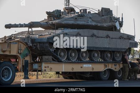 (140820) -- GAZA-GRENZE, 20. August 2014 -- Menschen reparieren einen LKW, der einen Merkava-Tank auf der Straße in Südisrael am Rande des Gazastreifens transportiert, am 20. August 2014. Israel werde die Offensive im Gazastreifen verstärken, bis der Raketenabwurf von dort auf Israel aufhört, sagte Premierminister Benjamin Netanjahu am Mittwoch, als Reaktion auf die erneuten Gaza-Raketenangriffe auf Zentral- und Südisrael zu Beginn des Tages. ) ISRAEL-GAZA-OFFENSIVE-VERSTÄRKUNG LixRui PUBLICATIONxNOTxINxCHN Gaza-Grenze 20. August 2014 Prominente Reparieren Sie einen LKW mit einem Merkava-Tank an der Straße in Südirael Borde Ring T Stockfoto