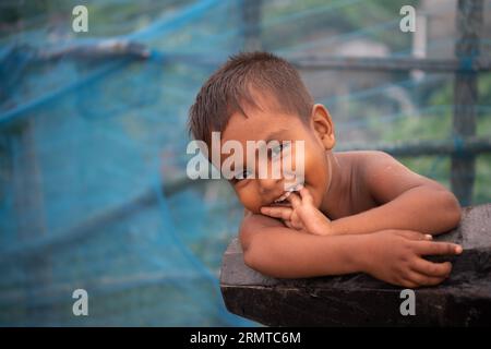 Ein Kind posiert für ein Foto am gebrochenen Ufer des Flusses Shibsha in Dakop Upazilla, Khulna. Vor nicht allzu langer Zeit war Kalabogi, ein Küstendorf in Bangladesch, voll von kultivierbarem Land, bis der Anstieg des Meeresspiegels begann, das Gebiet bis zur Bucht von Bengalen zu verschlingen. Häufige Zyklone und Überschwemmungen haben das Dorf seit den späten 1990er Jahren getroffen 2009 zerstörte ein großer Zyklon namens Aila die 1.400 Kilometer Dämme, 8.800 Kilometer Straßen und etwa 50.000 Hektar Ackerland. Mehrere hundert Menschen wurden bei der Katastrophe getötet. Die Bauern von Kalabogi waren die Stockfoto