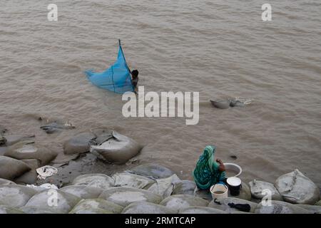 Ein Mann wird auf dem Fluss Shibsha beim Fischen und Fangen von Krabben gesehen. Vor nicht allzu langer Zeit war Kalabogi, ein Küstendorf in Bangladesch, voll von kultivierbarem Land, bis der Anstieg des Meeresspiegels begann, das Gebiet bis zur Bucht von Bengalen zu verschlingen. Häufige Zyklone und Überschwemmungen haben das Dorf seit den späten 1990er Jahren getroffen 2009 zerstörte ein großer Zyklon namens Aila die 1.400 Kilometer Dämme, 8.800 Kilometer Straßen und etwa 50.000 Hektar Ackerland. Mehrere hundert Menschen wurden bei der Katastrophe getötet. Die Bauern von Kalabogi wurden am schlimmsten getroffen. Wie die meisten Villen Stockfoto