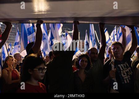 Menschen, die ein riesiges Banner bei einer Demonstration gegen Netanjahus Regierung halten. Tel Aviv, Israel. August 2023. Stockfoto