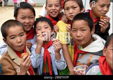 (140906) -- LUDIAN, 5. September 2014 -- Kinder essen Mondkuchen bei der vorübergehenden Neuansiedlung in der vom Beben heimgesuchten Longtoushan Township im Ludian County, Provinz Yunnan im Südwesten Chinas, 5. September 2014. Das Mid-Autumn Festival, das in diesem Jahr am 8. September stattfindet, ist ein traditioneller chinesischer Feiertag, an dem sich Familien unter Vollmond wiedervereinigen und Mondkuchen essen. Ein Erdbeben von 6,5 Magnitude erschütterte Ludian am 3. August, wobei mehr als 600 Menschen getötet und 80.000 Häuser zerstört wurden. ) (Ry) CHINA-YUNNAN-LUDIAN-MID-HERBSTFESTIVAL (CN) LinxYiguang PUBLICATIONxNOTxINxCHN 5. September 2014 Kinder essen Mondkuchen IM Tem Stockfoto