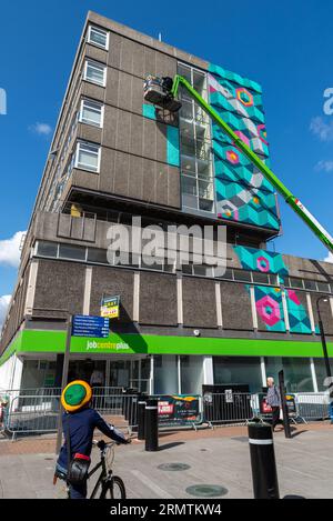 High Street, Southend on Sea, Essex, Großbritannien. 30. August 2023. Southend, das als Europas größtes Street-Art-Festival bezeichnet wird, feiert mit dem City Jam-Event seinen neuen Stadtstatus weiter. Über 200 lokale, nationale und internationale Straßenkünstler zeigen ihre Fähigkeiten an 100 Orten im Stadtzentrum. Einige provisorische Mauern wurden errichtet, aber die Künstler schmücken auch die Seiten von Gebäuden und andere dauerhafte Strukturen. Vom ersten bis zum dritten September haben die Künstler mit der Arbeit an den größeren Wandgemälden begonnen, um für die Veranstaltung bereit zu sein. Arbeiten in der Höhe über der High St Stockfoto