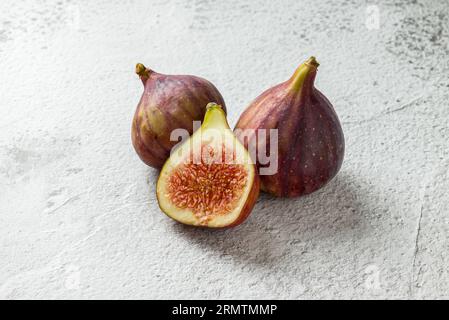 Ansicht ganzer und geschnittener organischer Feigen auf Steintisch Stockfoto