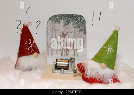 Zwei weihnachtselfen finden ein Carillon auf dem Schnee, die auf der rechten Seite versucht es zu drehen. Verspielter Stil, Schnee aus Baumwolle. Stockfoto