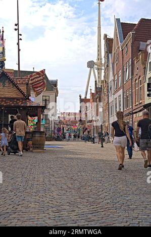 Alte malerische holländische Straße mit Uhrgiebel, Stufengiebelgebäude im alten Stadtzentrum. Eine Messe in der Shopping Street, wo Leute laufen Stockfoto