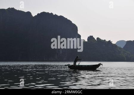 (140925) -- HA LONG BAY, 24. September 2014 -- Ein Fischerboot segelt durch Wasserstraßen zwischen den Inseln und Inselchen im Sonnenuntergang in Ha Long Bay, Nordvietnam, 24. September 2014. Die ha Long Bay im Golf von Tonkin umfasst etwa 1.600 Inseln und Inselchen und bildet eine spektakuläre Meereslandschaft aus Kalksteinsäulen. Aufgrund ihrer steilen Natur sind die meisten Inseln unbewohnt und nicht von einer menschlichen Präsenz betroffen. Die außergewöhnliche landschaftliche Schönheit der Stätte wird durch ihr großes biologisches Interesse ergänzt. Sie wurde 1994 in die UNESCO-Weltnaturerbe-Liste aufgenommen. VIETNAM-HA LONG BAY-WORLD HERITA Stockfoto