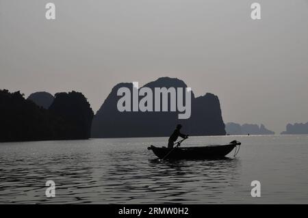 (140925) -- HA LONG BAY, 24. September 2014 -- Ein Fischerboot segelt durch Wasserstraßen zwischen den Inseln und Inselchen im Sonnenuntergang in Ha Long Bay, Nordvietnam, 24. September 2014. Die ha Long Bay im Golf von Tonkin umfasst etwa 1.600 Inseln und Inselchen und bildet eine spektakuläre Meereslandschaft aus Kalksteinsäulen. Aufgrund ihrer steilen Natur sind die meisten Inseln unbewohnt und nicht von einer menschlichen Präsenz betroffen. Die außergewöhnliche landschaftliche Schönheit der Stätte wird durch ihr großes biologisches Interesse ergänzt. Sie wurde 1994 in die UNESCO-Weltnaturerbe-Liste aufgenommen. VIETNAM-HA LONG BAY-WORLD HERITA Stockfoto