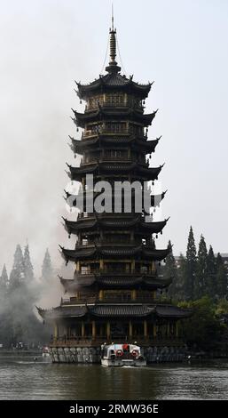 (141001) -- GUILIN, 1. Oktober 2014 -- Foto aufgenommen am 1. Oktober 2014 zeigt die Sonnenpagode, die im Tannensee in Guilin, der südchinesischen autonomen Region Guangxi Zhuang, Feuer fängt. Die bronzefarbene Betonpagode, die 41 Meter hoch war und aus 350 Tonnen Bronze bestand, fing am Mittwochmorgen Feuer. Die Feuerwehrleute setzten das Feuer ab, das mehr als zwei Stunden gedauert hatte. Die Doppelpagoden, genannt Sonne und Mond im Tannensee, wurden 2001 auf der Grundlage von etwas aus der Tang-Dynastie (618-907 n. Chr.) wiederaufgebaut. Sie gehören zu den touristischen Sehenswürdigkeiten von Guilin. ) (lfj) CHI Stockfoto