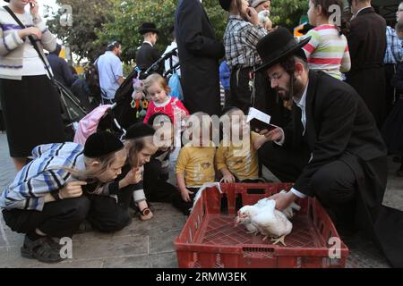 (141001) -- JERUSALEM, 1. Oktober 2014 -- Ultra-orthodoxe Juden schwingen sich ein weißes Huhn über den Kopf, während sie am 1. Oktober 2014 im Stadtteil MEA Shearim in Jerusalem ein Gebet im Rahmen der traditionellen Kaparot-Zeremonie vor dem heiligsten Tag des Judentums, Yom Kippur, lesen. Kaparot ist ein alter und mystischer Brauch, der mit dem jüdischen Versöhnungstag Jom Kippur verbunden ist und jederzeit zwischen Rosh HaShana (jüdisches Neujahr) und Jom Kippur durchgeführt werden kann. MIDEAST-JERUSALEM-YOM KIPPUR GilxCohenxMagen PUBLICATIONxNOTxINxCHN Jerusalem OKT 1 2014 Ultra-orthodoxe Juden schwingen ein weißes Huhn über den Kopf Stockfoto