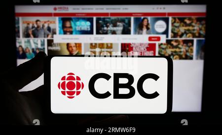 Person, die ein Smartphone mit dem Logo der Canadian Broadcasting Corporation (CBC) auf dem Bildschirm vor der Website hält. Konzentrieren Sie sich auf das Display des Telefons. Stockfoto