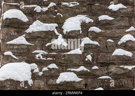 Mittelalterliche Steinmauer ist mit Schnee bedeckt, Design Hintergrund mit Platz für Text. Stockfoto