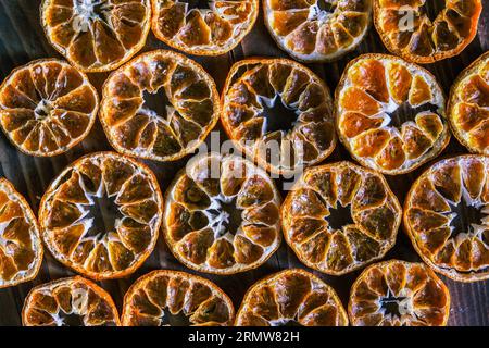 Getrocknete Orangenscheiben auf dem Holztisch. Trockene Zitrusfrüchte. Getrocknete Zitrusfrüchte auf dem Tisch. Obere Ansicht der orangefarbenen Schichten. Mandarinen- oder Mandarinenfrüchte Stockfoto