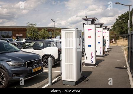 Ein Mann wartet, während sein Elektroauto am 13. August 2023 an einer Ionity-Ladestation an einer Autobahnraststation in Zentralfrankreich aufgeladen wird. IONITY ist ein Netz von Hochleistungs-Ladestationen für Elektrofahrzeuge zur Erleichterung des Fernverkehrs in ganz Europa. Es handelt sich um ein Joint Venture, das von der BMW Group, der Mercedes-Benz Group, der Ford Motor Company und der Volkswagen Group gegründet wurde. Andere Automobilhersteller sind jedoch eingeladen, das Netzwerk auszubauen. Stockfoto