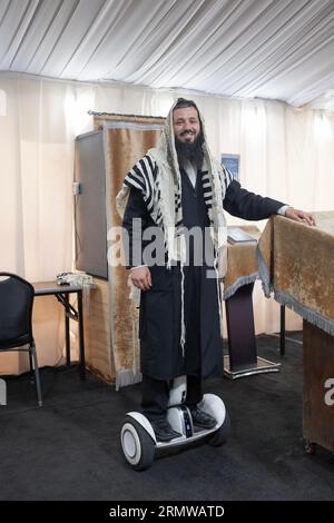 A sexton - shammash - at a synagogue with a few tents. His hoverboard lets him be everywhere at once. In Mosey, New York. Stockfoto