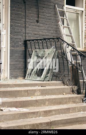 Raketenangriff in Kiew, Ukraine, august 2023. Zerbrochene Fenster und verschlossenes Glas auf Treppen nach der Explosion. Das Haus wurde durch den Sprengrupenkrieg in der Ukraine beschädigt Stockfoto