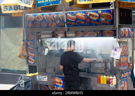 Ein Lebensmittelhändler in der Nähe der 7th Ave an der West 37th Street grillt Fleisch in einem rauchigen Meer. In Midtown Manhattan. Stockfoto