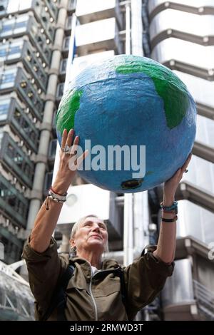 London, Großbritannien. 30. August 2023. Demonstranten der Extinction Rebellion zielten auf zehn Versicherungsunternehmen in der City of London und forderten sie auf, die East Africa Crude Oil Pipeline (EACOP) nicht zu versichern. „Oil Slickers“ in schwarz-weißer Lackierung marschierten lautlos durch die Straßen und vor jeder Versicherungsgesellschaft wurde symbolisches (gefälschtes) Öl über einen Globus gegossen, bevor es von einem Team in Gefahrgutanzügen gereinigt wurde. Quelle: Anna Watson/Alamy Live News Stockfoto