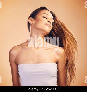 Schönheit, Haare und Zittern mit einer natürlichen Frau im Studio auf braunem Hintergrund für Keratin-Behandlung. Freiheit, Energie und Shampoo mit einem selbstbewussten Jungen Stockfoto