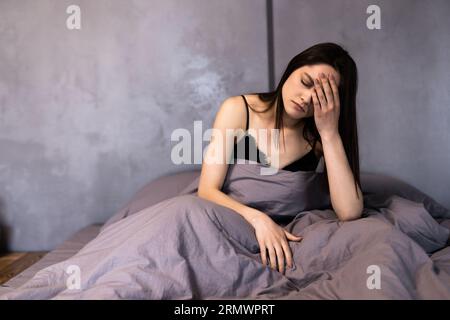 Nachdenklich entspannte junge Frau, die zu Hause im Bett liegt Stockfoto