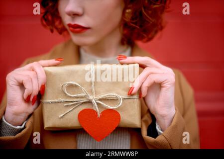 Frau ist nicht zufrieden mit einem kleinen Geschenk zu Weihnachten oder Valentinstag. Nahansicht auf rotem Hintergrund Stockfoto