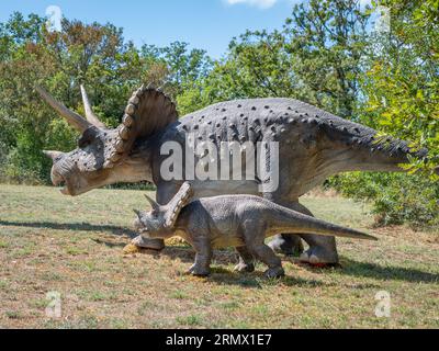 Zwei lebensgroße Nachbildungen von Dinosaurier-Skulpturen stehen in einem grünen Park in Lacave, Frankreich Stockfoto
