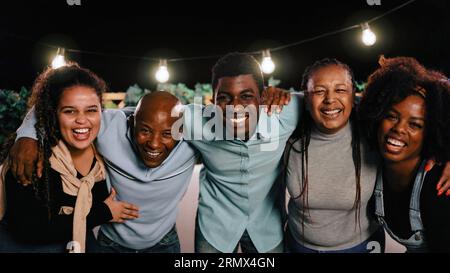 Glückliche afrikanische Familie, die Spaß daran hat, sich bei nächtlicher Ferienhausparty im Freien zusammenzufassen - Feier- und Beziehungskonzept - Fokus auf linke Tochter Stockfoto