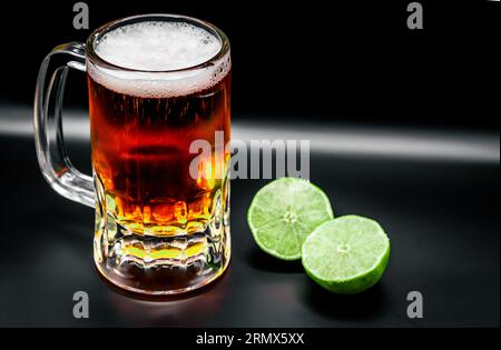 Bierbecher mit Zitronen auf schwarzem Hintergrund Stockfoto