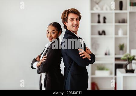 Partnerschaft. Geschäftsmann und schwarze Geschäftsfrau posieren nach erfolgreichem Deal, stehen hinter dem Rücken und lächeln Stockfoto