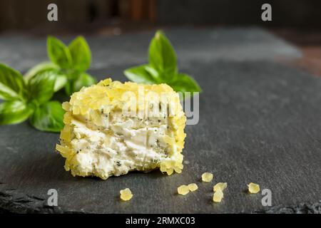 Frischer französischer Ziegenkäse mit Ananasstücken und Basilikum auf Schiefernaht Stockfoto