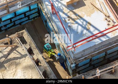 Bodenverdichtung mit Vibrationsplatte im Keller Stockfoto