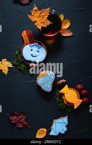 Herbsttee. Tasse Tee, bemalte Lebkuchen, Eicheln und Blätter auf schwarzem Hintergrund. Stockfoto