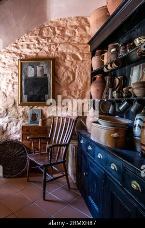 Töpferwaren auf Küchenkommode in Teal mit einem alten Holzstuhl. 18. Jahrhundert Umbau eines Blumenlofts in der Nähe von Penzance in Cornwall, Großbritannien Stockfoto