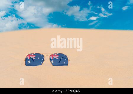 Sonnenbrillen mit Gläsern in Form einer australischen Flagge liegen auf Sand gegen blauen Himmel. Konzept von Sommerferien, Reisen und Tourismus in Australien Stockfoto