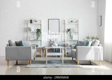 Helles Wohnzimmer mit gemütlichen grauen Sofas und Couchtisch Stockfoto