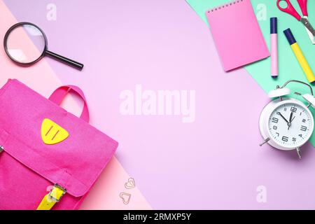 Stylischer Schulrucksack mit verschiedenen Schreibwaren auf farbigem Hintergrund Stockfoto